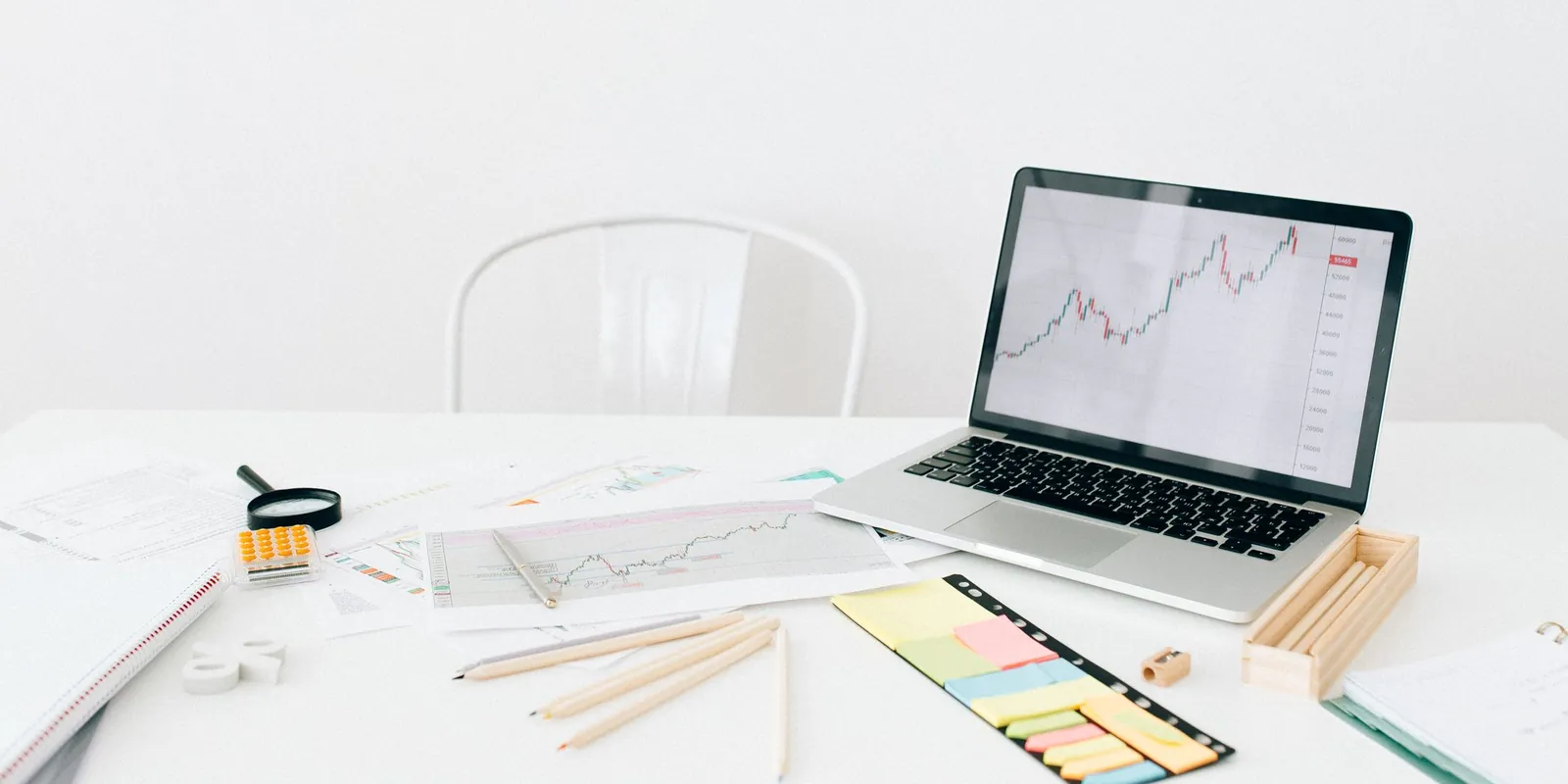 Clean desk with a laptop showing a chart, a magnifying glass, and sticky notes for a business audit